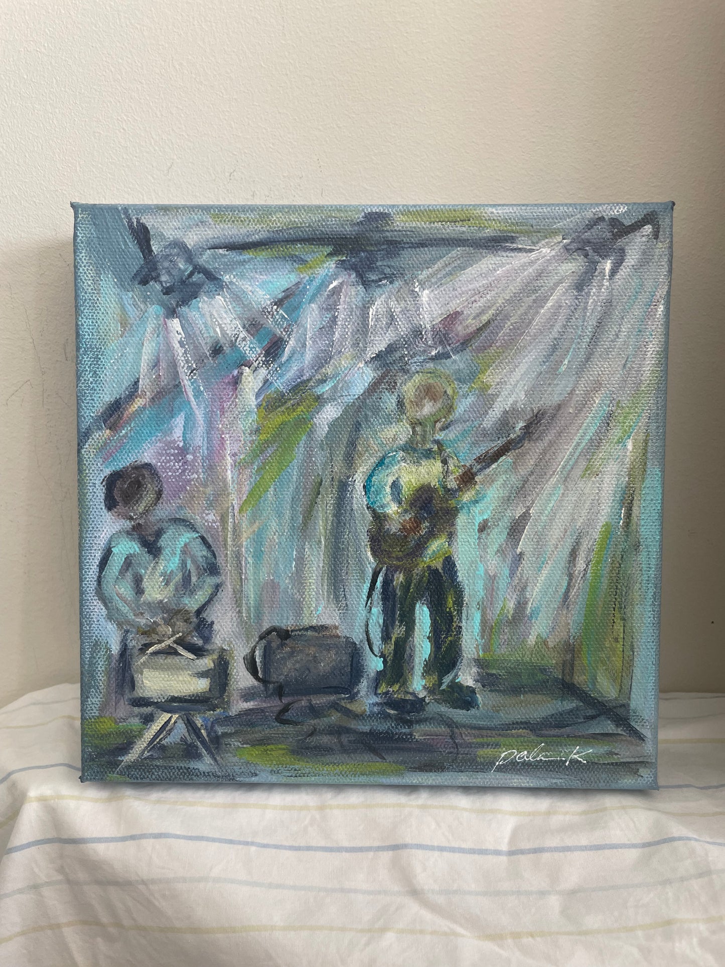 An expressive canvas painting of two musicians performing on stage under dramatic spotlights, displayed on a white fabric surface against a beige wall.